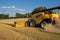Yellov combine on field harvesting gold wheat