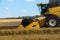 Yellov harvester on field harvesting gold wheat