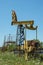 A yellow abandoned oil rig in a field against a blue sky. The concept of the decline of the oil industry. Oil ran out