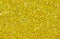 Yellow abstract background. Gold glitter closeup photo. Golden shimmer wrapping paper.