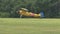Yellow airplane taxiing on grass field