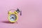 Yellow alarm clock with graduation cap on pink background closeup with copy space