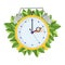 Yellow alarm clock moving forward in one hour with green leaves on background. Spring clock change concept.