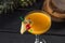 Yellow alcohol cocktail with pineapple and cherry in martini glass on black wooden table