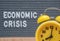 yellow analog alarm clock on the background of the inscription in English economic crisis