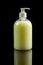 Yellow antiseptic liquid soap in a bottle with a dispenser on a black background. Side view, close-up. Vertical orientation