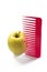 Yellow apple and a red plastic comb stuck