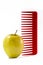 Yellow apple and a red plastic comb stuck