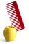 Yellow apple and red plastic comb stuck into it