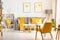 Yellow armchair in white living room interior with posters above