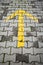 Yellow arrow on gray cobblestone pavement