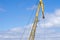 Yellow arrow of the port crane against the blue sky and clouds.