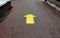 Yellow arrow sign on gray asphalt road showing direction forward