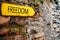 Yellow arrow sign on old stone brick wall. Direction pointer with inscription Freedom