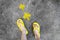 Yellow Arrows Direction. Womanâ€™s Sandals Feet with Violet Nail Pedicure on Cement Background