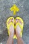 Yellow Arrows Direction. Womanâ€™s Sandals Feet with Violet Nail Pedicure on Cement Background