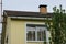 Yellow attic of a private house with a white window under a gray slate roof