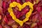 Yellow autumn leaves form a heart before red autumn leaves, for background