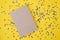 On a yellow background with confetti lies a blank notebook. Confetti is scattered around. Festive background