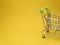On a yellow background, a grocery cart , the concept of starting school. Copy space