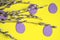 On a yellow background lie willow branches and purple paper eggs. Handicrafts for Easter from paper. composition at