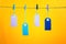 On a yellow background photographed labels. Four colorful empty labels hang on a rope pinned with clothespins. Bright