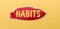 On a yellow background  a sheet of red paper with the word HABITS