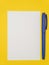 On a yellow background, a white sheet of paper and a blue ballpoint pen, the concept of starting school