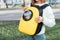 Yellow backpack with a transparent window porthole for walking and carrying cats. Concept of a hiking with pet in park or