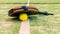 Yellow ball down of padel racket behind net on a green court grass turf outdoors