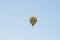 Yellow balloon against a blue sky. Aerostat. People in the basket. Fun. Summer entertainment. Romantic adventures.