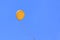 Yellow balloon flying in blue sky