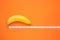 Yellow banana with measurement tape on orange background. Men penis size concept with empty free space for text or design