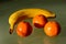 Yellow banana and orange color clementines groupped in closeup view on reflective glass