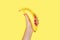 Yellow banana in women& x27;s hand with trendy manicure on yellow background.