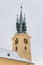 Yellow baroque church of St. James the Elder with gothic clock tower, medieval historical buildings, Main town square under snow