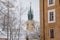 Yellow baroque church of St. James the Elder with gothic clock tower, medieval historical buildings, Main town square under snow