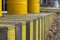 Yellow barrels on a wooden fence in the street. Yellow barrels of oil on the background of a row of yellow and black fences.