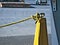 Yellow barrier rope attached to metal post with knot