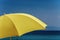 Yellow beach sun umbrella against blue sky.