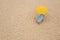 Yellow beach umbrella, sunbed and flip flops on sandy coast. Space for text