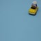 A yellow Beetle with a flower bow on the roof rides on a blue background. Copy space. Minimal car scene