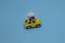 A yellow Beetle with a flower bow on the roof rides on a blue background. Copy space. Minimalistic car scene