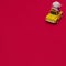 A yellow Beetle with a flower bow on the roof rides on a red background. Copy space. Minimal drive scene