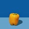 Yellow bell pepper on blue. A bright vegetable in a minimalist style. Pop art design, creative concept of summer food.