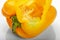 Yellow bell pepper cut sideways, with seeds inside, on a white background