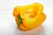 Yellow bell pepper cut sideways, with seeds inside, on a white background