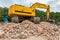 Yellow belt excavator on heap of bricks