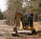 Yellow belt excavator in a pine forest. Hydraulic earthmoving harvester. Rotating operator's cab. Construction industry.