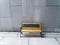 Yellow bench on white or gray concrete wall background